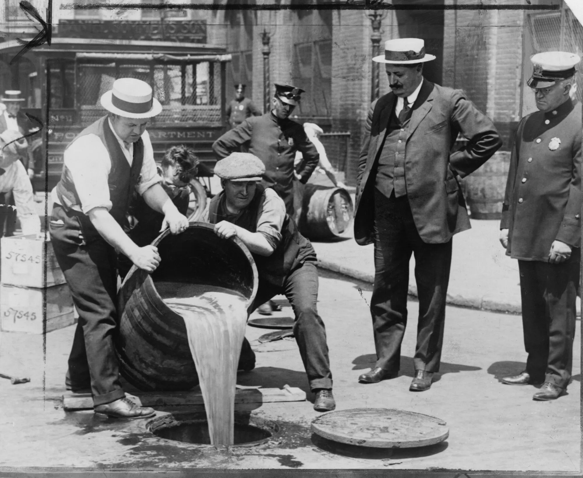 Des agents déversent dans un égout l’alcool saisi lors d’une descente, au plus fort de la prohibition, New York, 1921 ; à droite, le commissaire adjoint de police John A. Leach. Photo : Library of Congress. Licence : domaine public (image recadrée au bord du tirage et redimensionnée). Source : Wikimedia Commons
